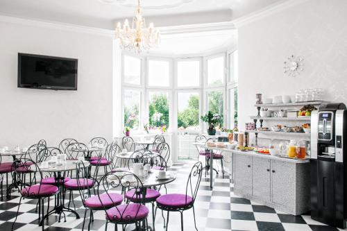 فندق بيلفيو أم كورفرستيندام  في برلين: مطبخ مع كراسي وردية وطاولات في غرفة