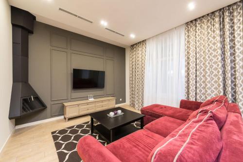 a living room with a red couch and a television at Riviera Zoloche Resort & Spa in Vishenki