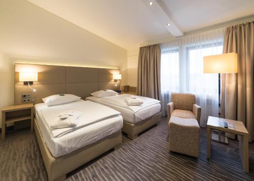 ein Hotelzimmer mit 2 Betten und einem Stuhl in der Unterkunft Hotel Gustav-Stresemann-Institut in Bonn