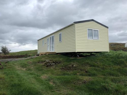 a small yellow house sitting on top of a hill at Lækjarkot Rooms and Cottages with Kitchen in Borgarnes
