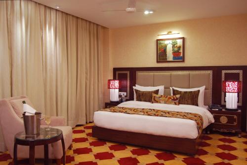 a hotel room with a large bed and a chair at HK Clarks Inn, Amritsar in Amritsar