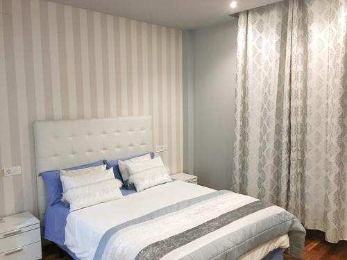 a bedroom with a large bed with blue and white sheets at VILLA CORASAO LUXURY in La Zubia