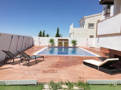 a swimming pool in a yard with two chairs and a building at VILLA CORASAO LUXURY in La Zubia