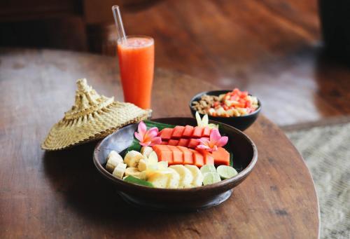 Villa Campuhan في Jasri: طبقين من الطعام على طاولة خشبية مع مشروب