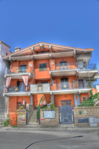 an orange apartment building with stairs and a blue door at Guest House Qui Dormì L'Etrusco in Canino