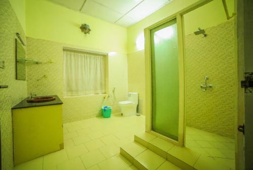 a bathroom with a toilet and a glass shower door at Tea tours Ripon Heritage Bungalow in Meppādi