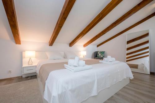 a white bedroom with two beds and wooden ceilings at Villa Bella in Banjol