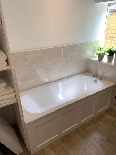 baño con bañera blanca y ventana en The Croft Apartment, en Bourton on the Water