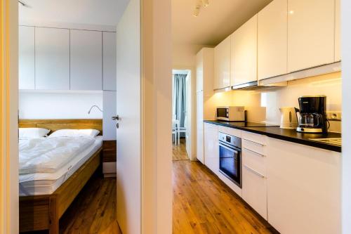 uma cozinha com armários brancos e uma cama num quarto em Vier Jahreszeiten 2-80 em Grossenbrode