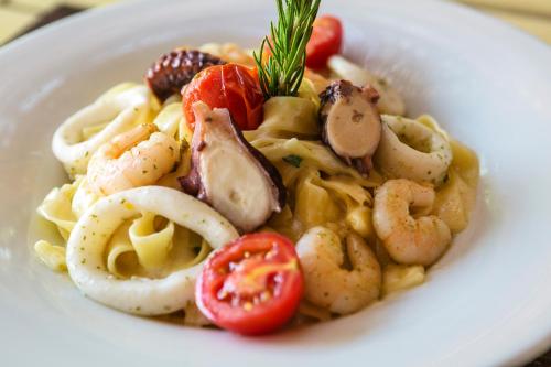 a white plate of pasta with shrimp and tomatoes at Faros Bodrum Hotel - Special Category in Golturkbuku