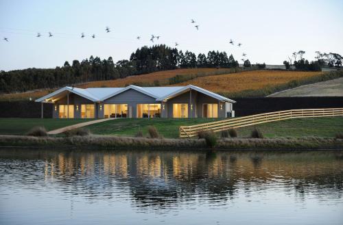 a house on a hill next to a body of water at Relbia Lodge in Relbia