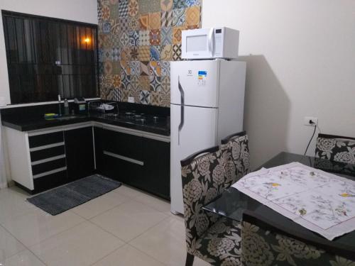a kitchen with a refrigerator and a table and a microwave at Residência Cidade Verde 4 in Maringá