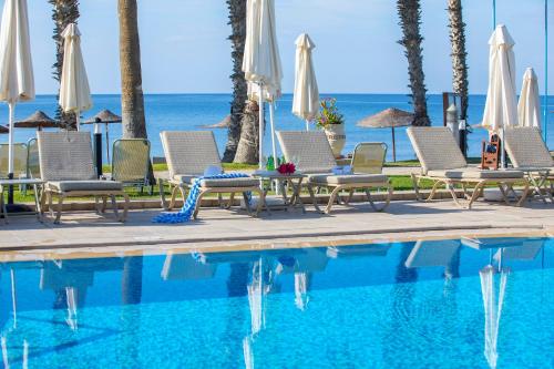 a swimming pool with chairs and umbrellas next to the ocean at Louis Ledra Beach in Paphos City