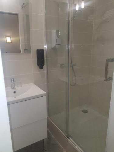 baño blanco con ducha y lavamanos en Hotel Nova en Montpellier