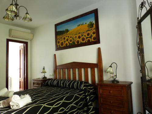 1 dormitorio con cama y una pintura de girasol en Casa La Antigua Almazara, en Cazorla