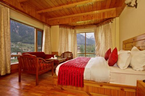 una camera da letto con un letto e una grande finestra di Hotel Hayer Regency a Manāli