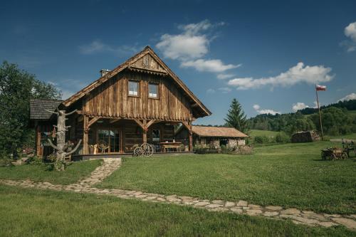ein großes Holzhaus mit einem Rasenhof in der Unterkunft Miejsce po Dworze in Polana
