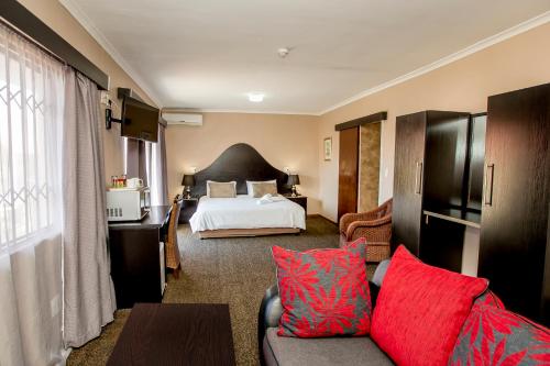 a hotel room with a bed and a couch with red pillows at Oria Guest House in Cape Town