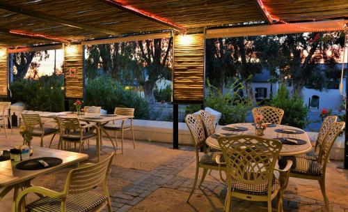 a patio with tables and chairs and windows at Mont d'Or Swartberg Hotel in Prince Albert
