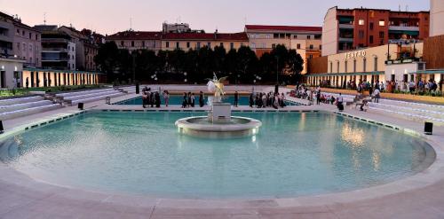una fuente en una ciudad con gente caminando alrededor de ella en Hotel Susa en Milán