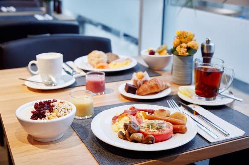 a table with plates of breakfast food on it at Lindner Hotel Antwerp, part of JdV by Hyatt in Antwerp