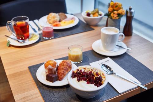 a table with plates of breakfast foods and cups of coffee at Lindner Hotel Antwerp, part of JdV by Hyatt in Antwerp