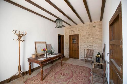 a living room with a wooden table and a brick wall at Cortijo El Derramadero in Villacarrillo