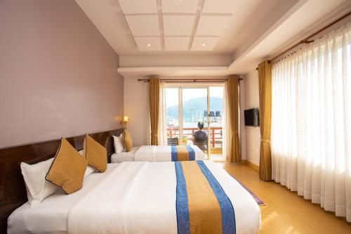 a hotel room with two beds and a balcony at Hotel Lake Paradise in Pokhara