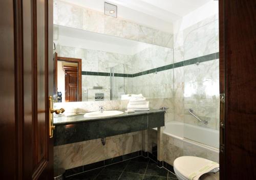 a bathroom with a sink and a tub and a mirror at Grand Hotel Praha in Prague