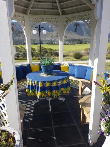 Mulligans Guest Lodge في هيرمانوس: شرفة مع طاولة زرقاء وكراسي صفراء