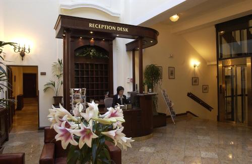 a lobby with a reception desk with flowers in the foreground at Grand Hotel Praha in Prague