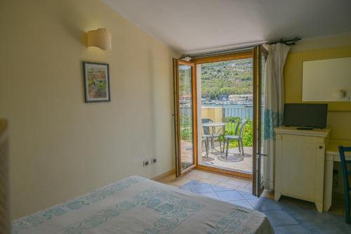 una camera con letto e porta di accesso a un balcone di Hotel Baja Romantica a Bosa