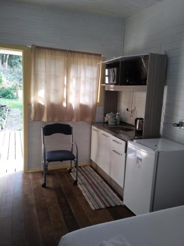 Il comprend une petite cuisine avec une chaise et un réfrigérateur. dans l'établissement Chalé da Tranquilidade, à Gramado
