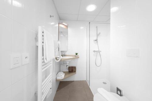 a white bathroom with a shower and a sink at Kyriad Lyon Est Stadium Eurexpo Meyzieu in Meyzieu