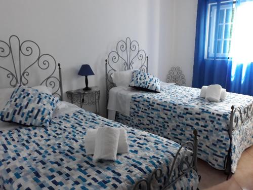 ein Schlafzimmer mit zwei Betten mit blau-weißer Bettwäsche in der Unterkunft Casa da Zi in Vila Nova de Milfontes