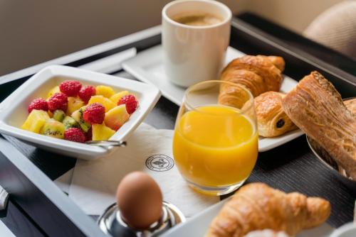 a tray of breakfast food with a bowl of fruit and a cup of coffee at Hôtel Le Presbytère in Paris