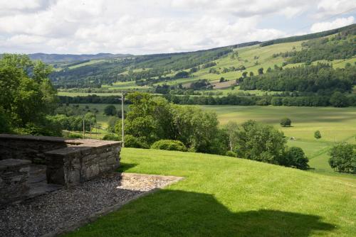een grasheuvel met uitzicht op de glooiende heuvels bij Craignuisq Farmhouse in Pitlochry