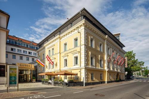 un edificio amarillo con banderas americanas en una calle en Hotel Sandwirth, en Klagenfurt