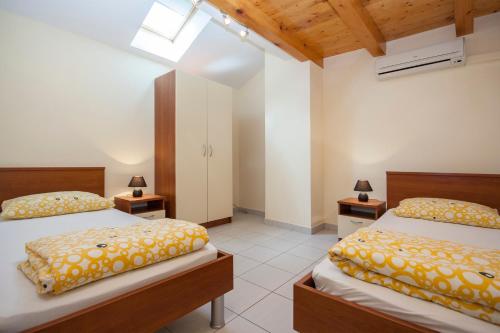two beds in a room with two lamps on tables at Apartments Maslina in Brodarica