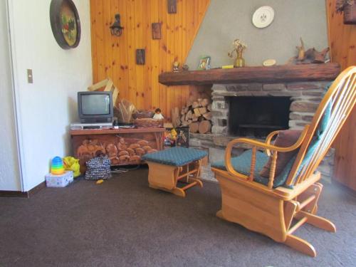 a living room with a fireplace and a rocking chair at Grande casa di famiglia in Temù