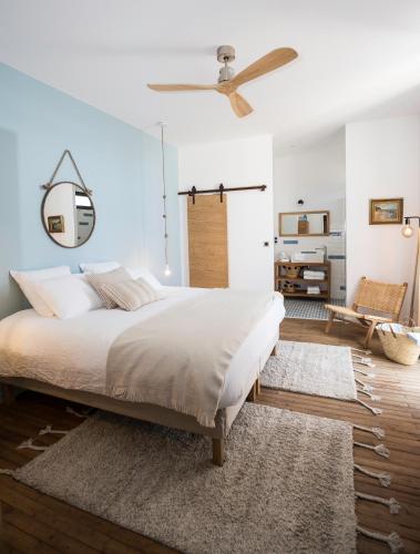 une chambre avec un grand lit et un ventilateur de plafond dans l'établissement L’Ostréale, à La Tremblade