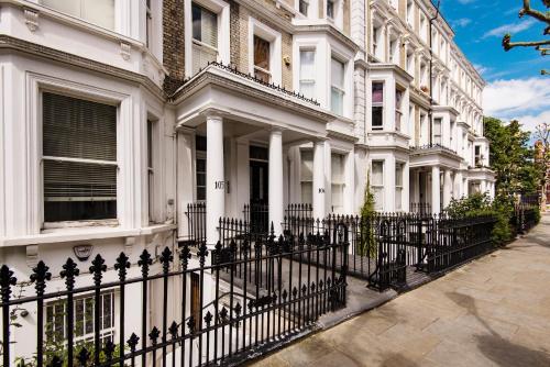 eine Reihe weißer Häuser mit einem schwarzen Zaun in der Unterkunft Bright Earl’s Court Apartment- SVA in London