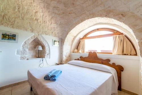 Schlafzimmer mit einem Bett und einem Fenster in der Unterkunft WePuglia - Trullo Rampone in Martina Franca
