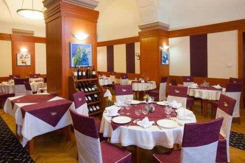 a restaurant with white tables and chairs and wine bottles at Arany Bárány Hotel in Zalaegerszeg