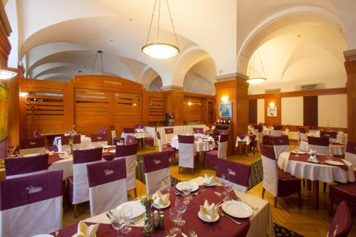 a restaurant with tables and chairs in a room at Arany Bárány Hotel in Zalaegerszeg