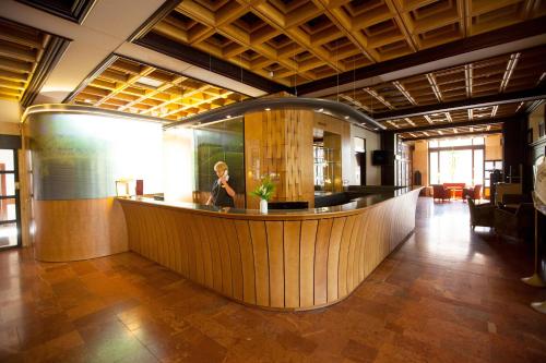 a lobby with a woman sitting at a bar at Arany Bárány Hotel in Zalaegerszeg