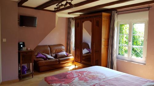 ein Schlafzimmer mit einem Bett, einem Sofa und einem Fenster in der Unterkunft L ANCIEN MOULIN A GRAINS in Valmont