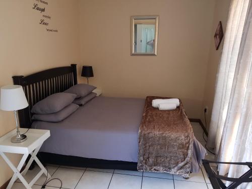a bedroom with a bed and a table and a lamp at Kgosi Lodge in Kimberley