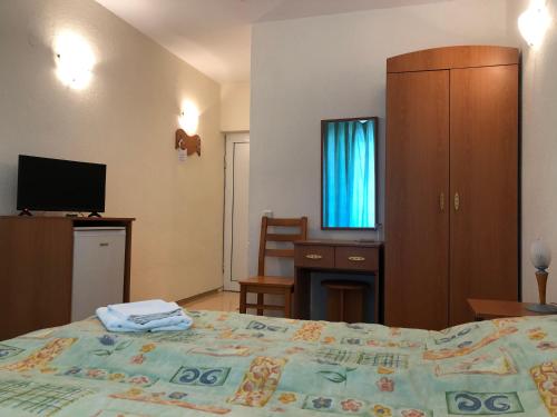 a bedroom with a bed and a desk and a television at Family Hotel Central in Kranevo
