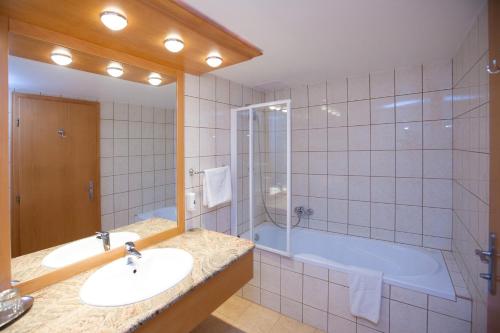 a bathroom with a tub and a sink and a shower at Arany Bárány Hotel in Zalaegerszeg